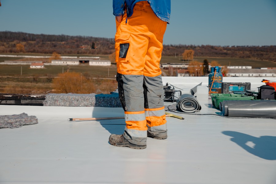 A man in orange pants and a blue shirt stands on a roof in South Florida
