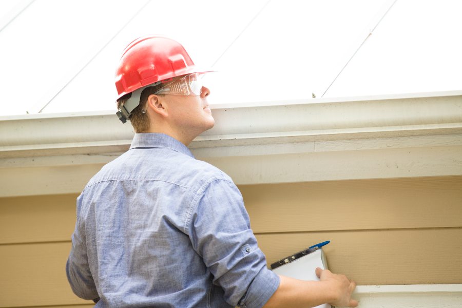 A man in a hard hat and safety glasses inspects a gutter in South Florida
