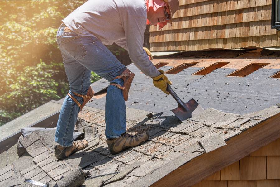 A man works on a roof, using a hammer to manage re-roofing challenges in South Florida
