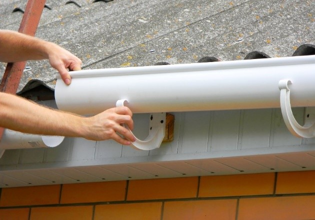A Man Installing a Gutter for Channeling Rainwater at Paul Bange Roofing in South Florida 