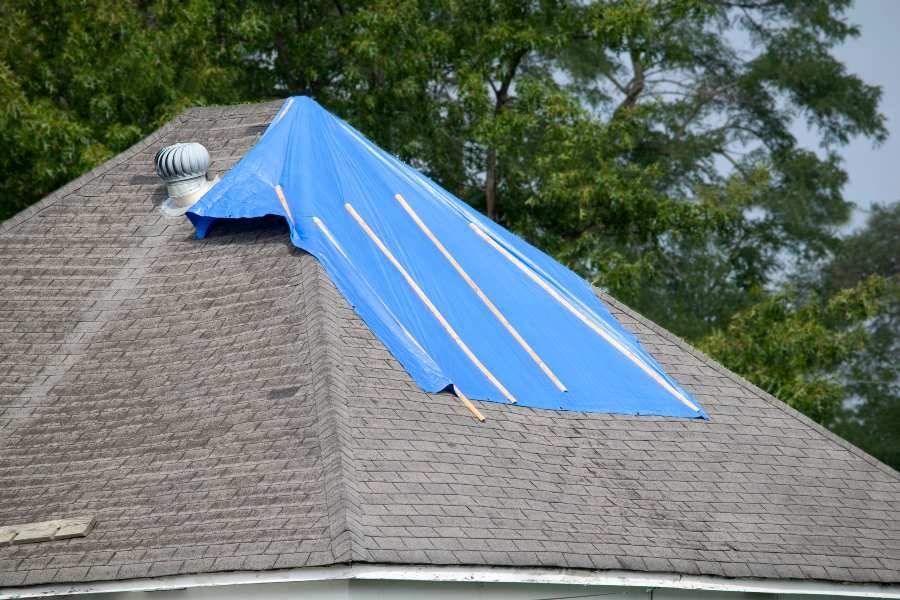 A blue tarp is placed over a house's roof, indicating ongoing roof maintenance in South Florida.